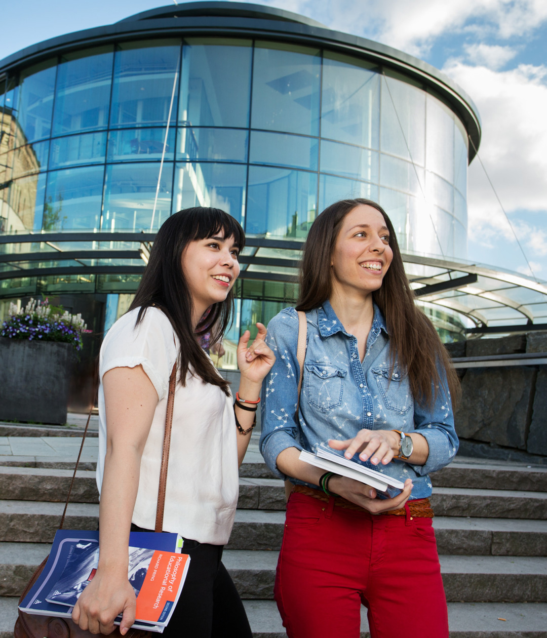 Two young students walk down steps outside the University of Gothenburg, showcasing the vibrant educational atmosphere of the city.